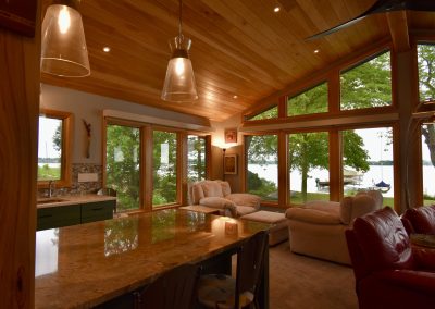 Interior golden shot of a custom lake home with wooden panel ceiling looking out over the lake.