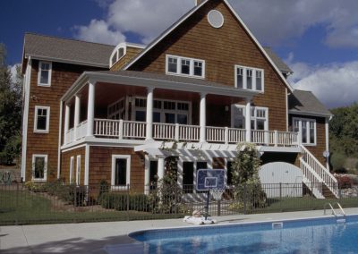 exterior poolside view of wooden-sided three story house